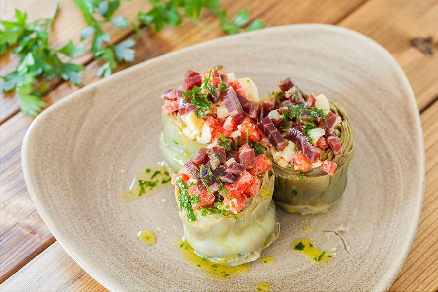 Alcachofas con tomate y aceitunas, plato saludable rico en fibra y antioxidantes, ideal para una alimentación equilibrada.